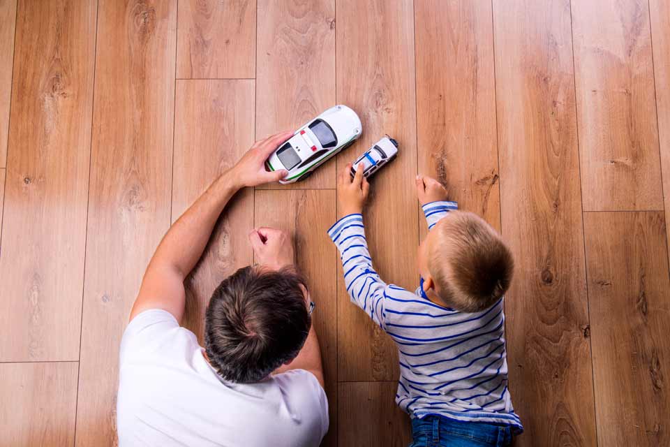 father playing with child on hardwood floors